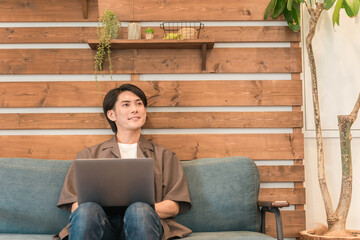 家でくつろぎながらノートパソコンをいじる若い男性
