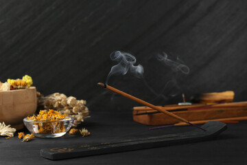 Aromatic incense stick smoldering in holder with om sign on black table. Space for text