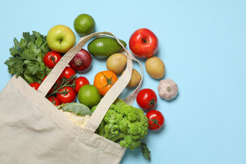 Delivery of vegetarian products. Bag with different vegetables and fruits on light blue background, top view. Space for text