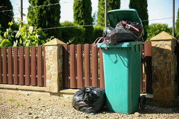 Trash bags full of garbage and bin outdoors