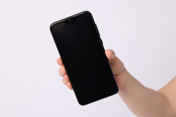 Woman holding smartphone with blank screen on white background, closeup