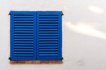 Blue window with shutters with brick windowsill with space on a white wall