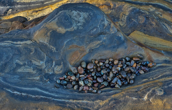 USA, California, Point Lobos State Natural Reserve. Blue and gold tone rocks at low tide with colorful small pebbles