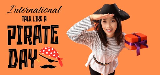 Young Asian woman dressed as pirate with gift on orange background. Banner for Talk Like a Pirate...