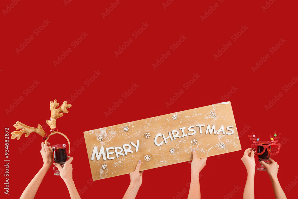 Wall mural female hands with glasses of warm mulled wine and christmas decor on red background