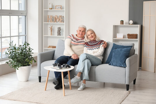 Happy mature couple sitting on sofa at home - Powered by Adobe