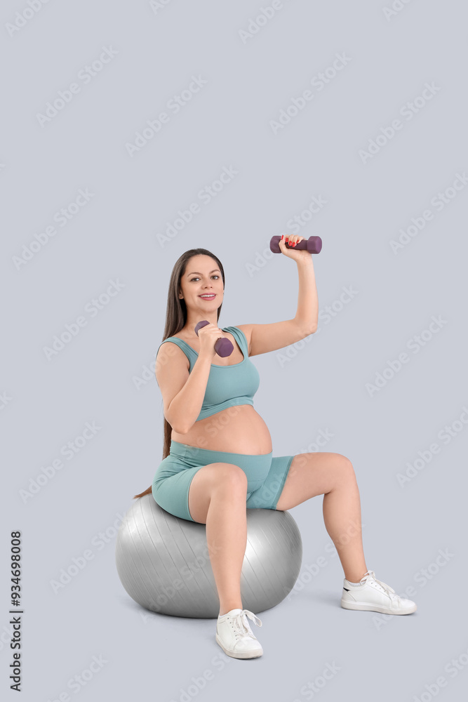 Canvas Prints sporty pregnant woman with dumbbells training on fitball against light background