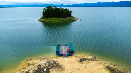 Aerial view of local ferry transporting cars, motorcycles and people across a river in Kanchanaburi...