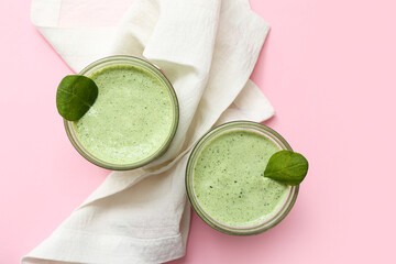 Glasses of fresh spinach smoothie on pink background