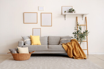 Interior of beautiful living room with cozy sofa, plaid, pillows and olive tree