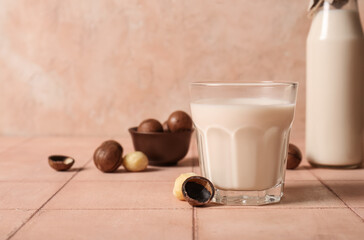 Glass and bottle of fresh macadamia milk on beige tile table