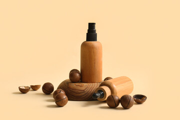 Macadamia nuts, wooden stand and bottles of cosmetic product on beige background