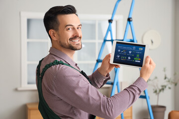 Male worker holding tablet computer with installed alarm system in room