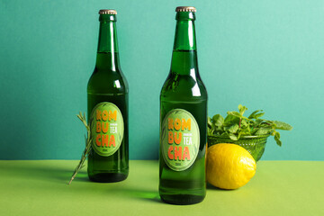 Bottles of tasty kombucha tea with lemon and mint on green background
