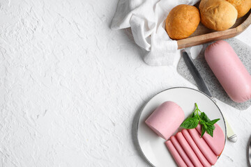 Plate with slices of tasty boiled sausage, bread and basil on grunge white background