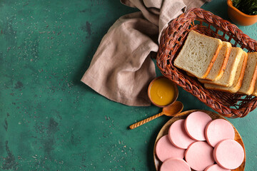Plate with slices of tasty boiled sausage, bread and mustard sauce on grunge green background