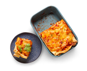 Baking dish and plate with tasty enchilada on white background