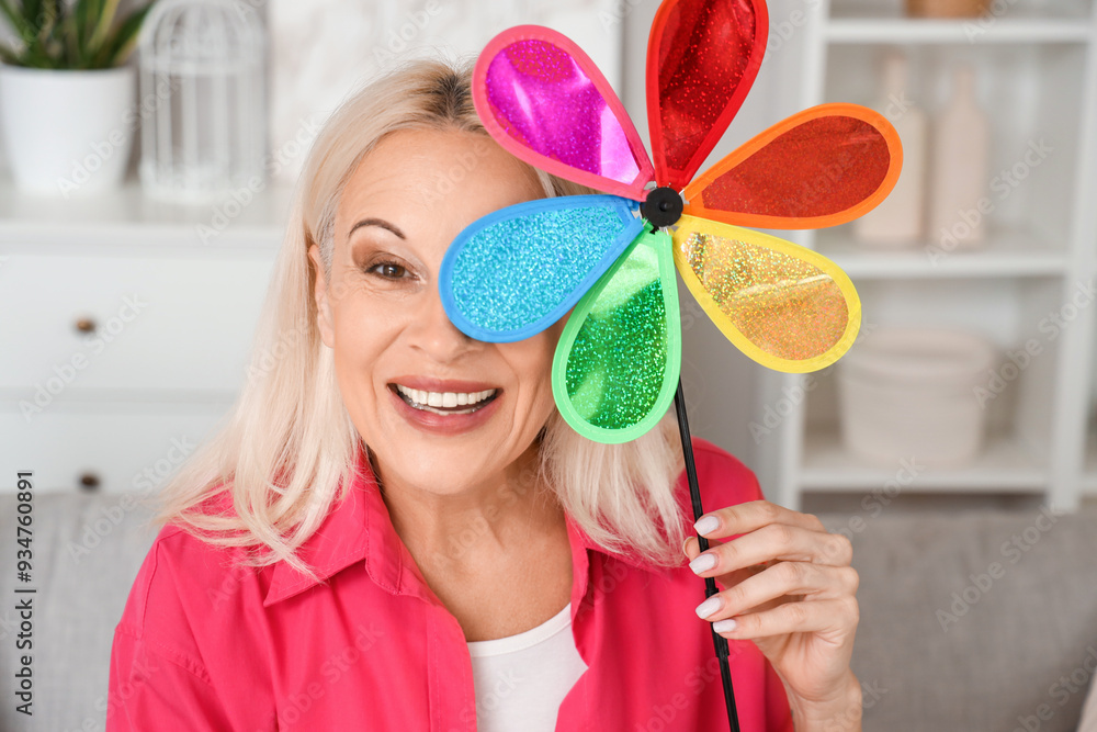 Wall mural mature woman with toy windmill at home, closeup