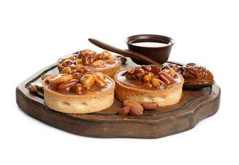 Tasty tarts with nuts and caramel sauce on wooden board against white background