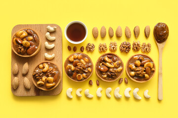 Tasty tarts with many different nuts and caramel on yellow background