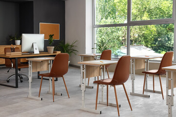 School desks with chairs in modern classroom prepared for exam