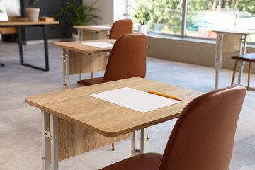 School desks with sheet of paper and pencil prepared for exam. Closeup