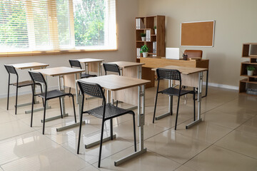 Interior of modern classroom with desks and chairs at school
