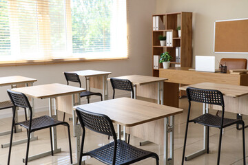 Interior of modern classroom with desks and chairs at school