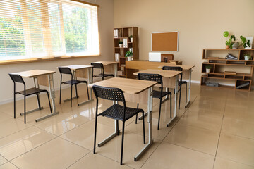 Interior of empty classroom with desks and chairs at school