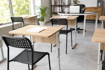 Desks with papers and chairs in modern empty classroom