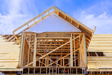Installation of plywood on wooden roof trusses for house that is being constructed