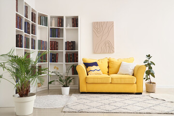 Yellow sofa and bookshelves with many books in light living room