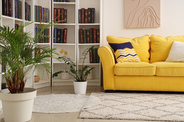 Yellow sofa and bookshelves with many books in light living room