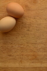 Dos huevos color beige en tabla de madera, alimento, natural, saludable, nutritivo, textura suave ,forma circular, huevos, proteina, crudo, entero ,cáscara ,calcio ,clara ,yema ,amarillo, 