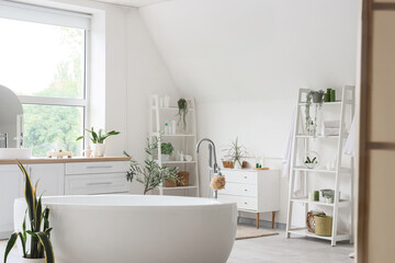 Interior of light bathroom with counters, shelf units and bathtub