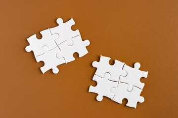 White plain jigsaw puzzle on chocolate brown background. Business concept. 