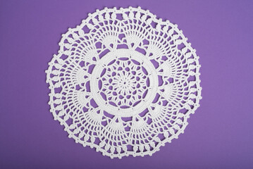 Crochet lace doily on purple background