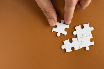Hand holding puzzle pieces, completing jigsaw puzzle. business concept. Selective focus.