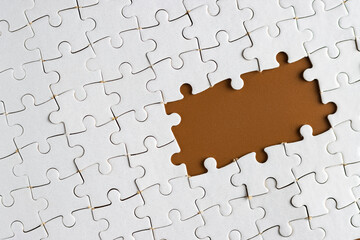 Blank chocolate brown background with white jigsaw puzzle. Empty space for copy space. Business...
