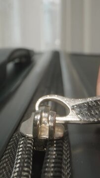 Vertical video. Dolly slider, close up. Fingers pull the zipper shut, securing luggage in anticipation of a journey that promises fascinating exploration and adventure.