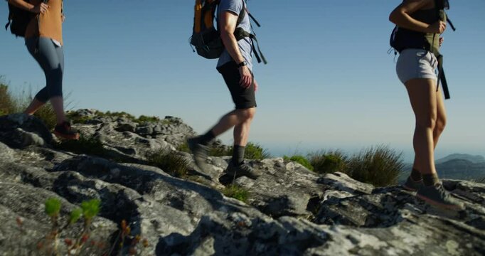 Hiking, group and mountain top as view ocean horizon for holiday fitness, adventure explore on cliff. Men, women or climbing backpack gear in sunshine rock or nature walking, athletic or teamwork