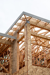 Obraz premium New residential home construction in framing stage, looking up at roof rafter detail through window openings at interior wood stud framing 
