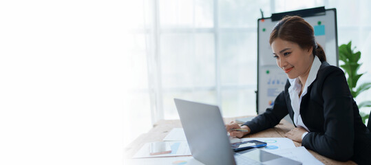 woman meticulously plans a finance audit, using a computer and calculator to review budget documents and ensure accuracy