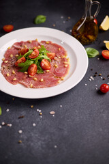 cooking tuna carpaccio - Fresh raw tuna fillet with olive oil and pine nuts on white ceramic plate