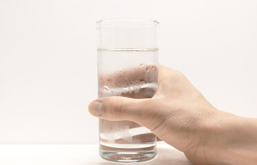 A human hand holding a cold glass of water