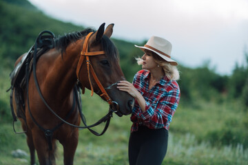 Obraz premium Happy blonde with horse in forest. Woman and a horse walking through the field during the day. Dressed in a plaid shirt and black leggings.