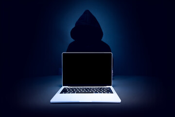 A laptop with a blank screen sits against a dark background, symbolizing the ominous nature of...
