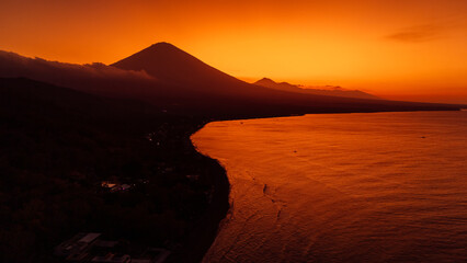 Panoramic view of coastline with volcano and sunset with quiet ocean in Bali.