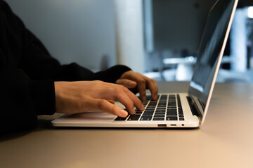 A person sits in the dark, typing on a laptop, symbolizing the dangers of cyberspace. The scene represents cybercrime, with themes of hacking, identity theft, and compromised network security, emphasi