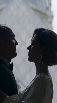 Happy couple near the Louvre museum pyramid in Paris. Action. Side view of embracing bride and groom.